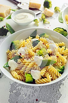 Pasta with green vegetables broccoli, Mange tout and creamy sauce in white plate