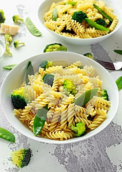 Pasta with green vegetables broccoli, Mange tout and creamy sauce in white plate