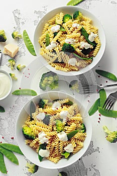 Pasta with green vegetables broccoli, Mange tout and creamy sauce in white plate