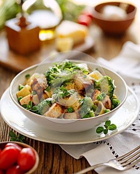 Pasta with grilled chicken breast, broccoli and green peas, sprinkled with parmesan cheese and fresh herbs