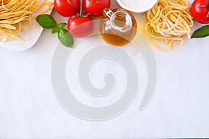 Pasta ingredients, above view top border against a white marble background