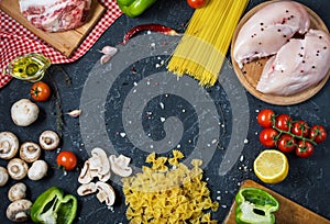 Pasta ingredients. Chicken breasts, Cherry tomatoes, spaghetti pasta, bacon and mushrooms on the stone table. Top view