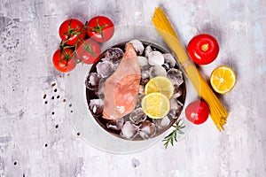 Pasta ingredients. Chicken breasts, tomatoes, spaghetti pasta, and lemon on the stone table.