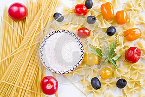 Pasta ingredients, raw pasta, cherry tomatoes, olives, salt and basil leaves