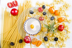 Pasta ingredients, raw pasta, cherry tomatoes, olives, salt and basil leaves