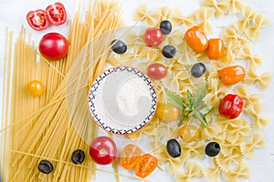 Pasta ingredients, raw pasta, cherry tomatoes, olives, salt and basil leaves