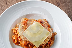 Pasta, Italian food, with tomato sauce topping with deep fried crispy pork cutlet and a sheet of cheese in white dish