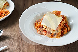 Pasta, Italian food, with tomato sauce topping with deep fried crispy pork cutlet and a sheet of cheese in white dish