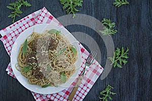 Pasta with meatballs and parsley in tomato sauce. Dark wooden background. View from above