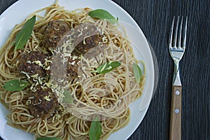 Pasta with meatballs and parsley in tomato sauce. Dark wooden background. View from above