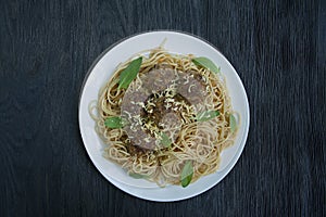 Pasta with meatballs and parsley in tomato sauce. Dark wooden background. View from above