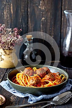 Pasta with meatballs and tomato sauce on a wooden background
