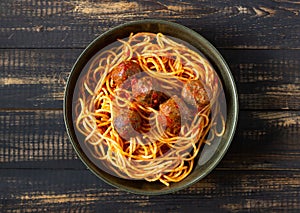 Pasta with meatballs and tomato sauce on a wooden background