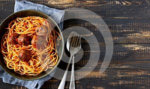 Pasta with meatballs and tomato sauce on a wooden background