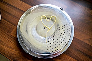 Pasta noodle heart shaped lying on pot cover