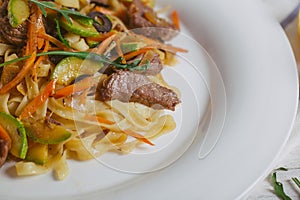 Pasta with olive meat greens on a white plate