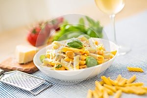 Pasta penne with chicken pieces mushrooms basil parmesan cheese and white wine. Italian food in white plate on kitchen