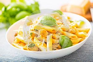 Pasta penne with chicken pieces mushrooms basil parmesan cheese and white wine. Italian food in white plate on kitchen