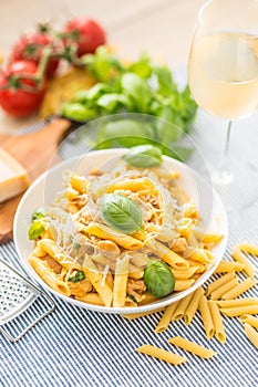 Pasta penne with chicken pieces mushrooms basil parmesan cheese and white wine. Italian food in white plate on kitchen