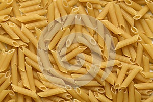 Pasta Penne Rigate background, top view.