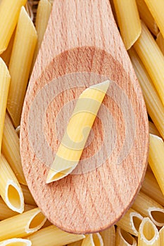 Pasta Penne in wooden spoon background full frame.