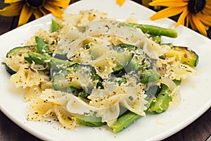 Pasta Primavera - it`s delicious, hearty and healthy dishes from South Italy. Wooden rustic background with flowers. Top