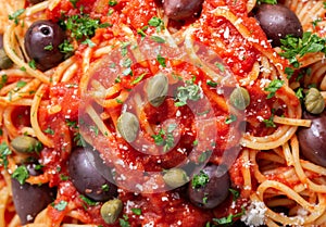 pasta puttanesca with olives, tomato sauce, anchovies and capers as background