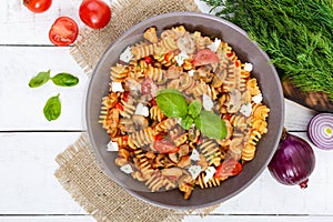 Pasta Radiatori with chicken, mushrooms, cherry tomatoes, feta cheese and tomato sauce on a white wooden background.