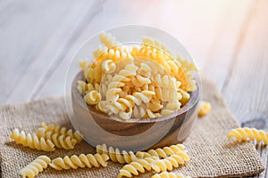 Pasta raw macaroni on wooden bowl background, close up raw macaroni spiral pasta uncooked delicious fusilli pasta for cooking food