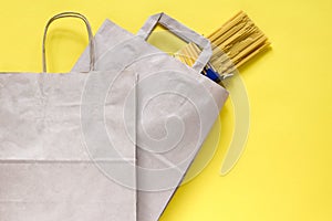 Pasta in recycled brown paper shopping bag with handle, on yellow background, flat lay, mockup. Food delivery. Empty package.