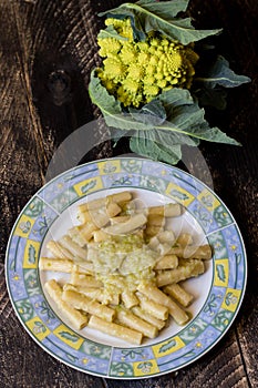 Pasta rigata with organic romanesco broccoli sauce on black wooden background