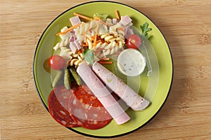 A pasta salad accompanied by tomatoes, sauce and sausage