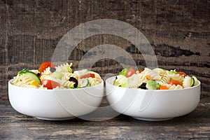 Pasta salad in a bowl on rustic wooden background