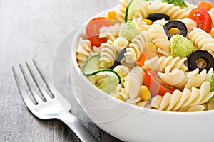 Pasta salad in a bowl on rustic wooden table