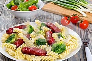 Pasta salad with broccoli and grilled sausages decorated with d