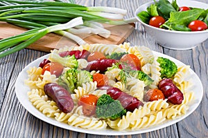 Pasta salad with broccoli, grilled sausages and tomatoes