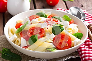 Pasta salad with fresh red cherry tomato and feta cheese. Italian cuisine