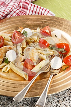 Pasta salad with mozzarella, cherry tomatoes and basil