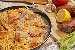 Pasta with salami in a pan, lemon, garlic