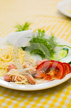 Pasta with sausage and tomatoes with greens on a white plate