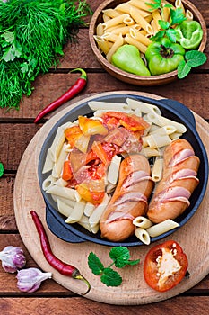 Pasta with sausages and lecho. Wooden rustic background. Selective focus. Top view