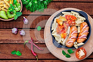 Pasta with sausages and lecho. Wooden rustic background. Selective focus. Top view