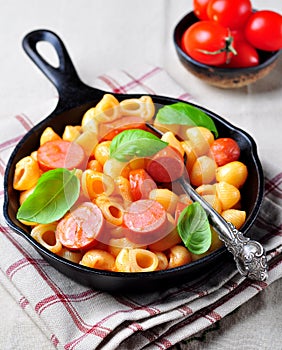 Pasta with sausages in tomato sauce with basil and cheese
