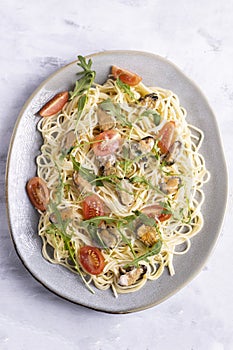 Pasta with seafood garnished with rocket salad and and tomatoes