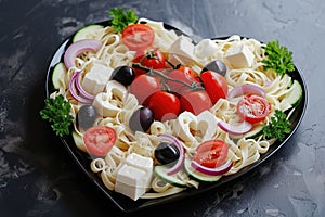 Pasta in the shape heart salad with tomatoes, cucumbers, olives, mozzarella and red onion Greek style