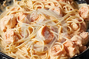 Pasta with shrimp cream sauce in frying pan, spaghetti with seafood, rich cream on saucepan