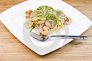 Pasta with shrimp and herbs in white dish