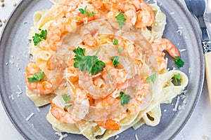Pasta with shrimps in creamy parmesan cheese and garlic sauce garnished with parsley, fettucini alfredo, horizontal, top view, photo