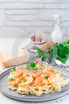 Pasta with shrimps in creamy parmesan cheese and garlic sauce garnished with parsley, fettucini alfredo, vertical, copy space photo