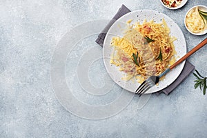 Pasta spaghetti with bacon egg cheese on a plate with spices. Traditional Italian dish Carbonara. Grey concrete table. Copy space